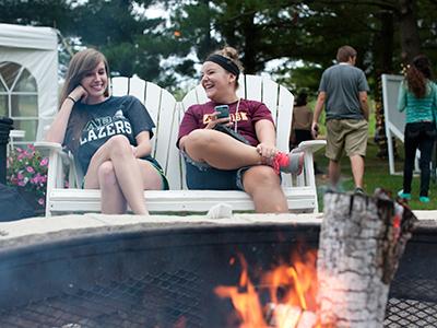 Two students hang out in front of a bonfire