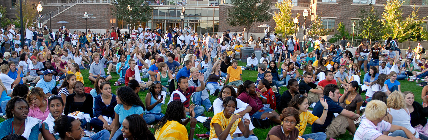 A large groups sits on the grass outside Coffman 