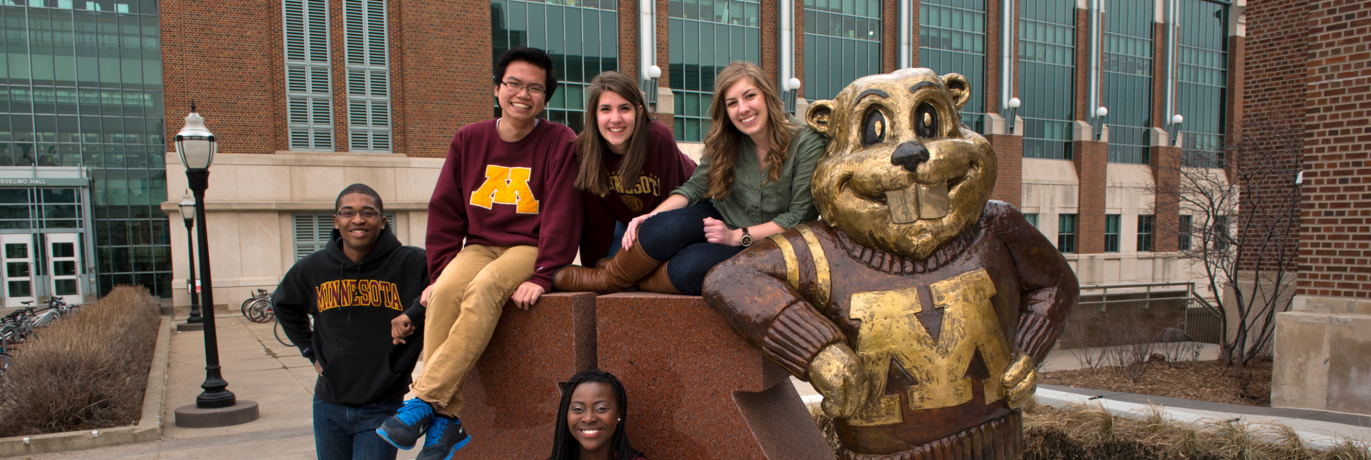Students pose in front of the Block M Goldy statue