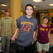 An incoming freshman and his parents pull suitcases during move in