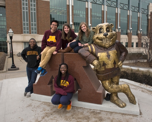 Students pose in front of the Block M Goldy statue